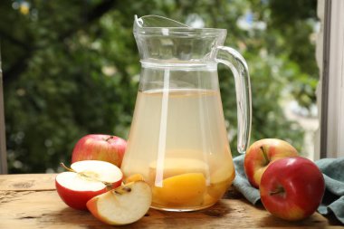 Cam sürahide lezzetli bir karışım ve açık havada ahşap masada taze elmalar.