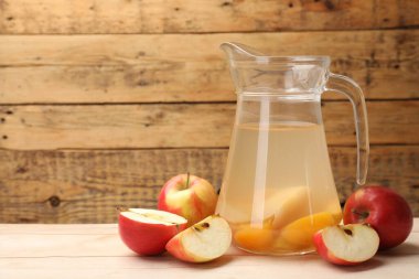 Cam sürahide lezzetli bir karışım ve ahşap masada taze elmalar, mesaj için yer.