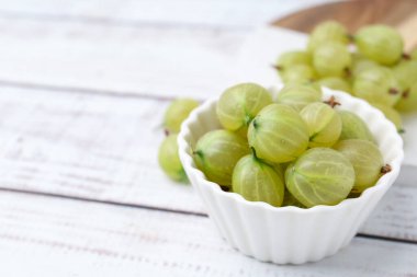 Taze yeşil bektaşi üzümleri, beyaz ahşap masada, yakın plan. Metin için boşluk