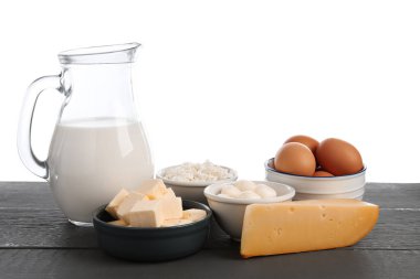 Gri ahşap masada beyaz arka planda farklı süt ürünleri ve yumurtalar