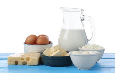 Farklı süt ürünleri ve yumurtalar mavi ahşap masada beyaz arka planda