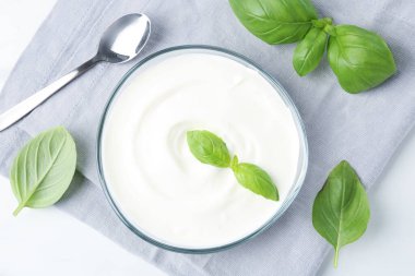 Lezzetli yoğurt ve fesleğen beyaz masada, düz yerde.