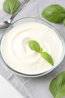 Lezzetli yoğurt ve fesleğen beyaz masada, yakın plan.