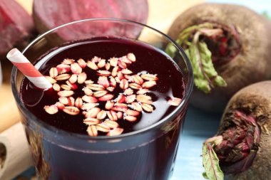 Süper yemek. Cam yulaflı lezzetli meyve suyu ve açık mavi masada pancar kökü, yakın plan.