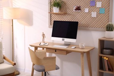 Ev ofisinde ahşap masası, bilgisayarı ve kırtasiyesi olan şık bir iş yeri. İç tasarım