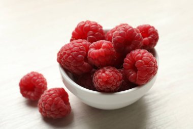 Beyaz ahşap masada taze taze ahududu, yakın plan.