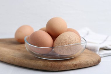 Beyaz masadaki kasede çiğ tavuk yumurtası, yakın plan.