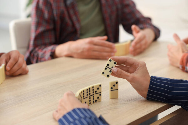 Друзья играют в домино за светлым деревянным столом, крупным планом
