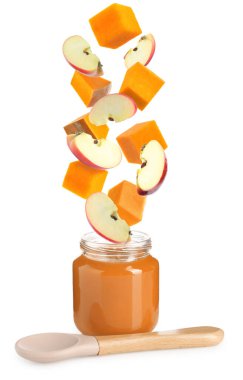 Bebek maması. Elma ve balkabağı dilimleri beyaz arka planda püre kavanozuna düşer.