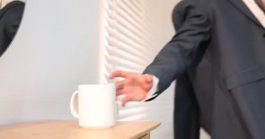 Genç adam bir fincan kahve alıp evde hazırlanıyor, kamera hareket ediyor.