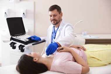 Klinikte kadının tiroid bezini ultrason taraması yapan sonograf.