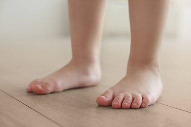 Çocuk sıcak zeminde çıplak ayakla dikiliyor, yakın plan. Yeraltı ısıtması