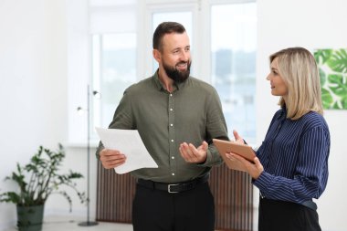Tabletle gülümseyen iş ortakları ofiste birlikte çalışıyorlar.