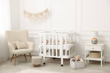 Rahat beşik, koltuk ve oyuncakları olan şık bir bebek odası.