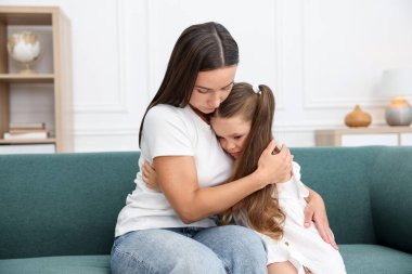 Anne evde üzgün kızını destekliyor ve ona sarılıyor.