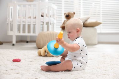 Işık odasında halıdaki oyuncakla oynayan sevimli bir bebek.