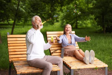 Güzel yaşlı çift parkta sabun köpüğüyle eğleniyor.