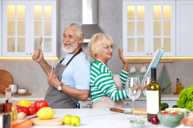 Yaşlı çift mutfakta birlikte yemek pişirirken eğleniyor.