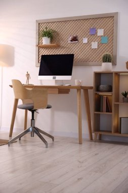 Ev ofisinde ahşap masası ve bilgisayarı olan şık bir iş yeri. İç tasarım