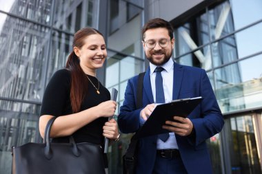 Mutlu iş arkadaşları ofis binasının yakınında düşük açılı bir şeyler tartışıyor.
