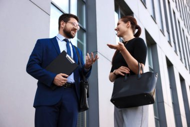 Mutlu iş arkadaşları ofis binasının yakınında düşük açılı bir şeyler tartışıyor.