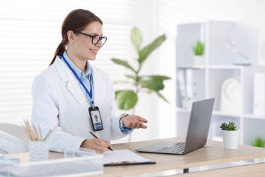 Teletıp. Doktor içeride bilgisayarla hastayla görüntülü konuşma yaparken not alıyor.