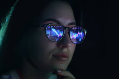 Siyah arka planda yansıması olan gözlüklü genç bir kadın, yakın plan.