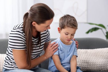 Anne evdeki kanepede üzgün oğlunu destekliyor.