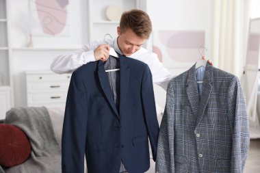 Hazırlanıyor. Genç adam evde kıyafet seçiyor.