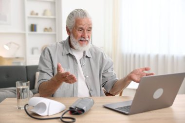 Üst düzey bir adam kapalı bir masada dizüstü bilgisayarla doktorla görüşüyor.
