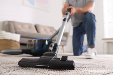 Halıyı elektrikli süpürgeyle temizleyen adam, yakın plan.