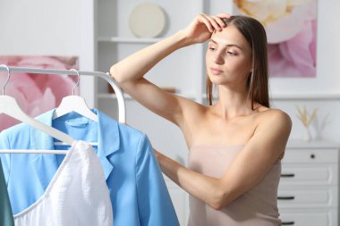 Hazırlanıyor. Evde kıyafet seçen genç bir kadın.