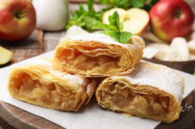 Lezzetli elmalı turta parçaları pudra şekeri, nane ve ahşap masada meyveler, yakın plan.