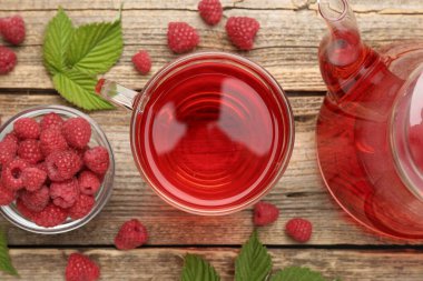 Lezzetli ahududu çayı, böğürtlen ve yapraklar ahşap masada, düz uzanmış