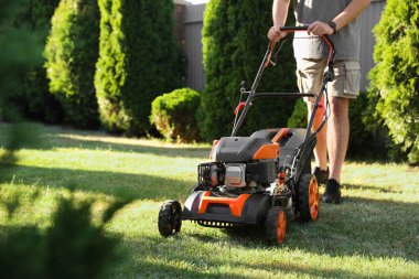 Bahçede çim biçme makinesiyle çim biçen adam, yakın plan. Metin için boşluk
