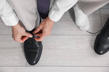 Hazırlanıyor. Genç adam evde şık ayakkabılar giyiyor, yakın plan.