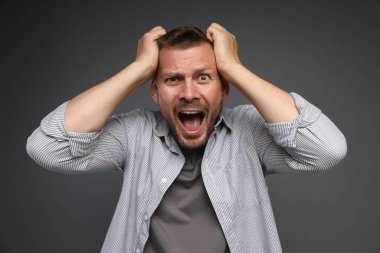 Gri arka planda panik atak geçiren bir adam.