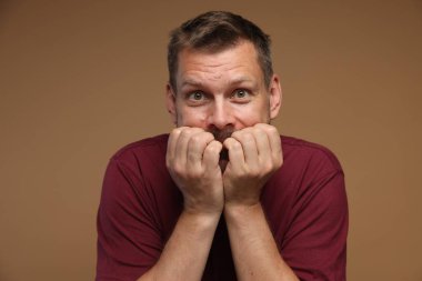 Kahverengi arka planda panik atak geçiren bir adam.