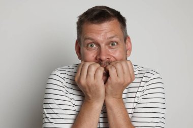 Açık gri arka planda panik atak geçiren bir adam.