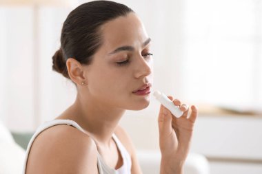 Evde dudak kremi olan genç bir kadın var.