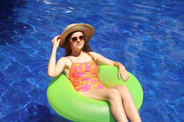 Güneşli bir günde yüzme havuzunda şişme halkalı bir kız.