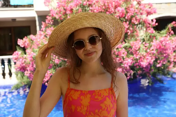 Güneşli bir günde yüzme havuzunun yanında hasır şapkalı bir kız.
