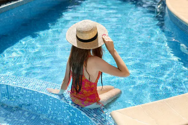 Yüzme havuzunda hasır şapkalı bir kız.