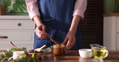 Tahta masada doğal vücut ovucu yapan kadın, yakın plan.