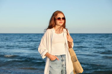 Güneş gözlüklü ve çantalı güzel bir genç kız.