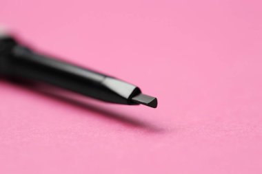 Pembe arka planda kaş kalemi bük, yakın plan. Metin için boşluk