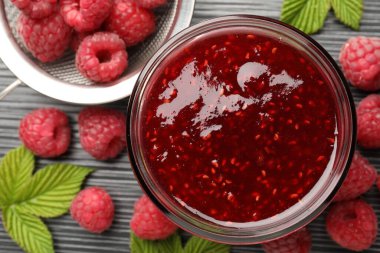 Cam kavanozda tatlı ahududu reçeli ve koyu gri ahşap masada böğürtlen.