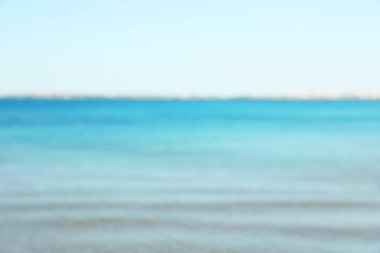 Açık mavi gökyüzünün altında güzel bir deniz, bulanık bir manzara.