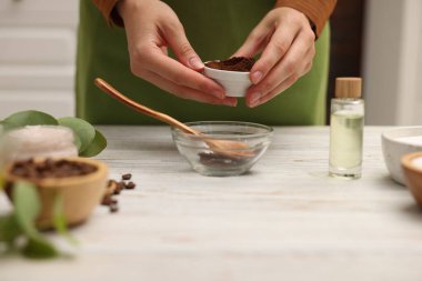 Doğal temizlik yapıyorum. Beyaz ahşap masada kahveye kahve katan kadın, yakın plan.