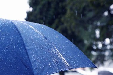Sağanak yağmur altında mavi şemsiye, yakın çekim.
